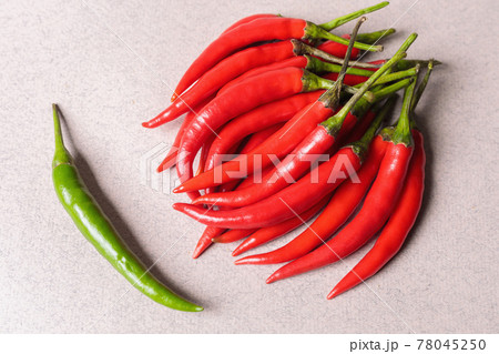 Slide of red chili peppers with one green on a light background. Slide of red chili peppers with one green on a light background. 78045250