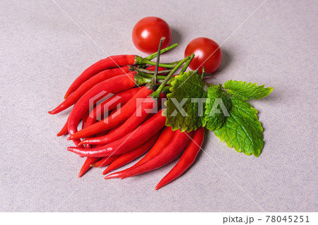 Slide of red chili peppers with one red tomato on a light background. 78045251