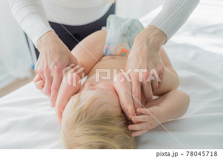 Mom does baby gymnastics for the baby's legs. Close-up. 78045718