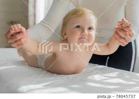 Mom does hand exercises to the baby. Close-up. 78045737