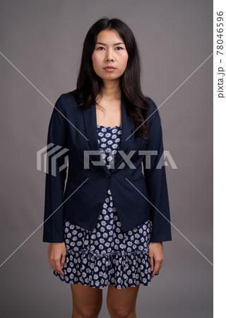 Asian woman wearing blue dress and cardigan sweater against gray 78046596