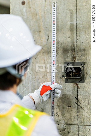 建築現場でメジャーを使う女性作業員 78047668