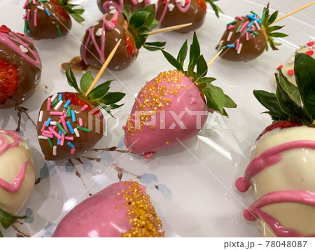 Beautiful bright colorful tasty sweet juicy fresh variety of strawberries in tampered white and dark milk Belgian chocolate with festive decoration and decor. A romantic dessert for a gift Beautiful bright colorful tasty sweet juicy fresh variety of strawberries in tampered white and dark milk Belgian chocolate with festive decoration and decor. A romantic dessert for a gift 78048087