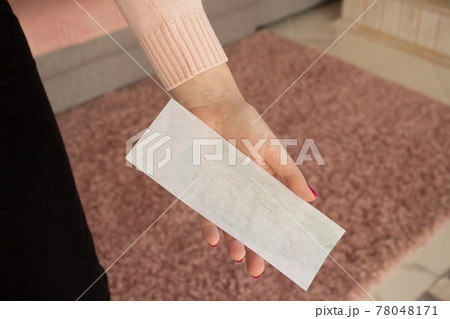 Hair removal wax strips with hair close-up in the hands of a young woman. Body hair removal concept with wax and sugaring at home or spa salon 78048171