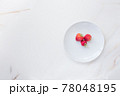Three strawberries on a large white dish with copy space. The concept of spring and berries from your vegetable garden 78048195