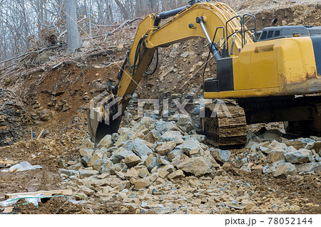 A large powerful loader overloads a pile of crawler excavator pours stones A large powerful loader overloads a pile of crawler excavator pours stones 78052144