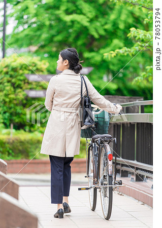 エコバックをカゴ 籠 に入れて自転車を引くビジネスウーマンの写真素材