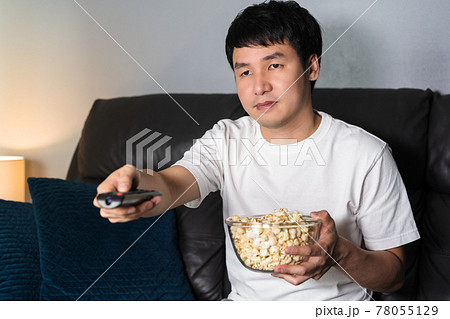 man watching TV on sofa at night 78055129