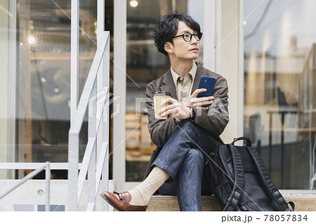 テイクアウトカップとスマホを持ったメガネをかけた30代前半の男性 78057834