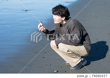 冬の江ノ島海岸で貝殻を拾う男性 78060437