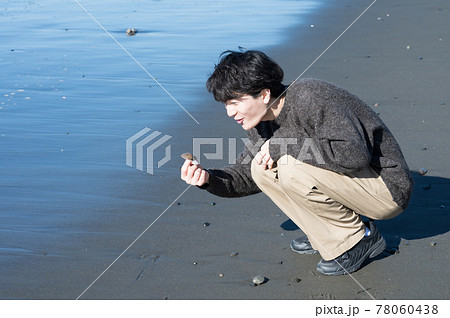 冬の江ノ島海岸で貝殻を拾う男性 78060438
