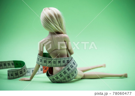 Closeup of Doll wrapped in measuring tape on green background -  female fight for a perfect body - Dieting concept 78060477