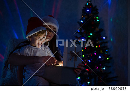 Exciting Mom and son open a glowing gift box at a magical Christmas night Exciting Mom and son open a glowing gift box at a magical Christmas night 78060853