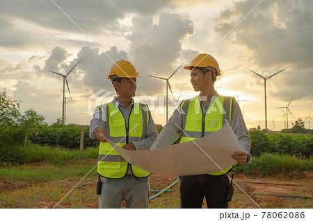 Teamwork of Asian windmill engineer group, worker working, holding a plan on site at wind turbines field or farm, clean energy source. Eco technology for electric power. industry nature. People 78062086