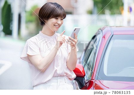 車を停めてスマホで電話をかける若い女性 78063135