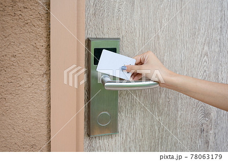 Hand holding key card scanning to unlock wooden door at resort 78063179