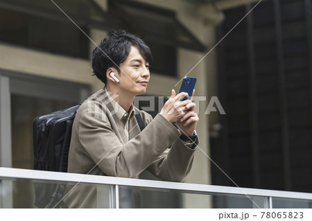 ヘッドホンをしてスマホを操作する30代前半の男性 ヘッドホンをしてスマホを操作する30代前半の男性 78065823