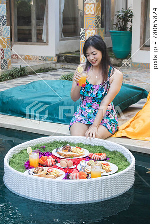Pretty Asian woman eating breakfast in the pool, floating breakfast. Pretty Asian woman eating breakfast in the pool, floating breakfast. 78065824