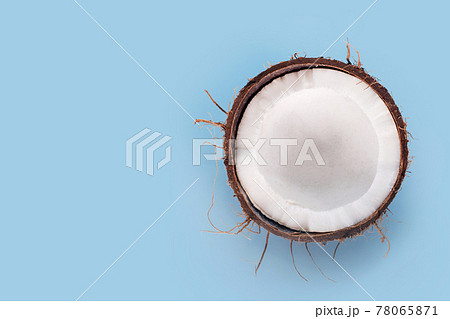 Cracked in half coconut on light blue background. Halved fresh raw coconut, free space for text 78065871
