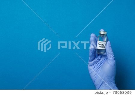 Hand in medical glove hold vaccine on blue background 78068039