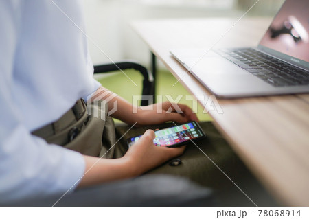 仕事中にスマートフォンでサボる女性 仕事中にスマートフォンでサボる女性 78068914