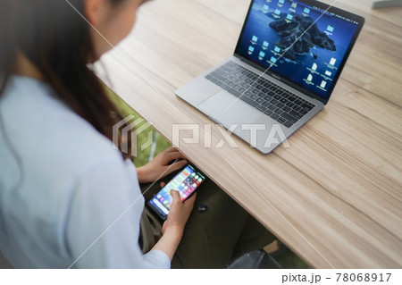 仕事中にスマートフォンでサボる女性 78068917