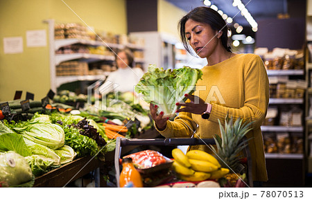 Woman shopping at store, walking among shelves 78070513