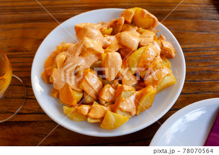 Spanish cuisine patatas bravas served with sauce on plate on wooden table Spanish cuisine patatas bravas served with sauce on plate on wooden table 78070564