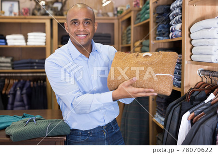 Seller offering suit jacket in menswear boutique 78070622
