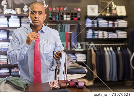 Man choosing new tie in clothing boutique Man choosing new tie in clothing boutique 78070623