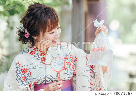 金魚すくいでおもちゃを釣る女性 78071567