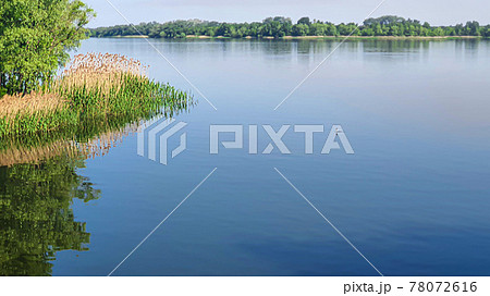Nature and empty beach on the river. Preparing for the summer season. Reflection of trees in the water. 78072616