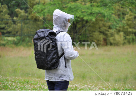 雨の中バックパックにカバーをかける 78073425