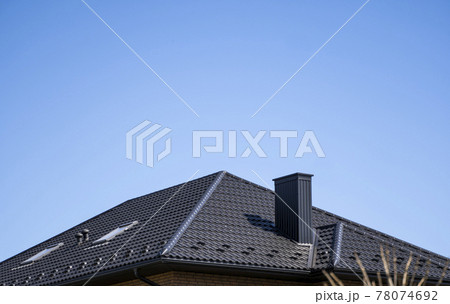 Brown corrugated metal profile roof installed on a modern house. The roof of corrugated sheet. Roofing of metal profile wavy shape. Modern roof made of metal. Metal roofing. 78074692