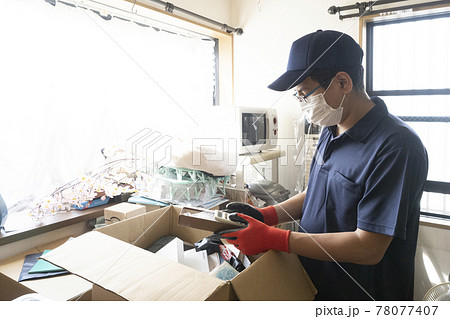 散らかった部屋の片付けをする男性作業員 78077407