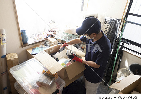 散らかった部屋の片付けをする男性作業員 78077409