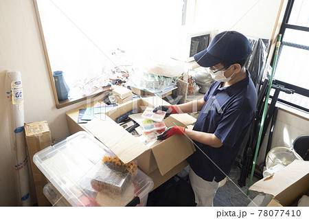 散らかった部屋の片付けをする男性作業員 78077410