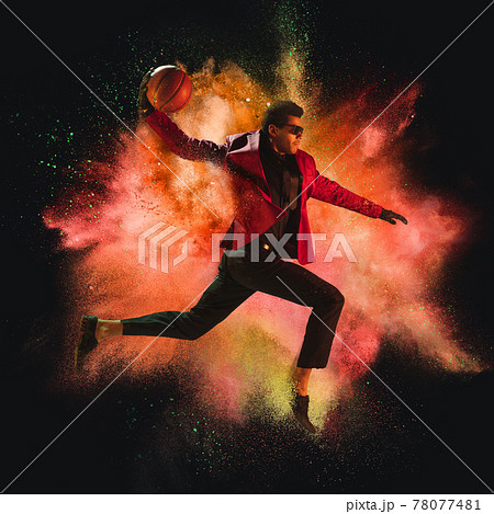 One young sportsman basketball player in explosion of colored neon powder isolated on dark background One young sportsman basketball player in explosion of colored neon powder isolated on dark background 78077481