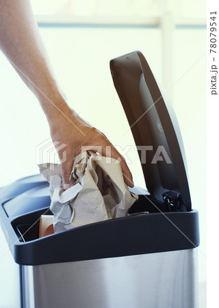 man throwing paper to a home recycling bin 78079541