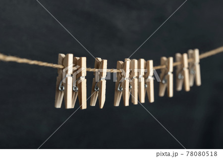 Wooden clothespins on rope on black background. Laundry concept. Wooden clothespins on rope on black background. Laundry concept. 78080518