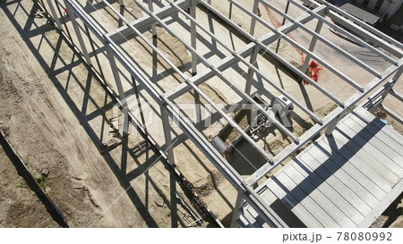 Reinforced Concrete Frame Of An Industrial Building. Camera Flight On A Construction Site. Beams With Steel Reinforcement. Dump Truck Unloads Sand in Construction. Aerial view. Unloading soil 78080992