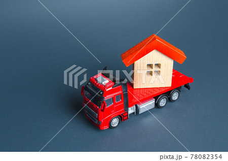 Truck transporting a house. Delivery services to another house. A moving company. Transportation of real estate. Resettlement program for new housing. Construction industry. Building insurance. 78082354