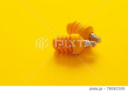 Light bulb on yellow paper background top view 78082500