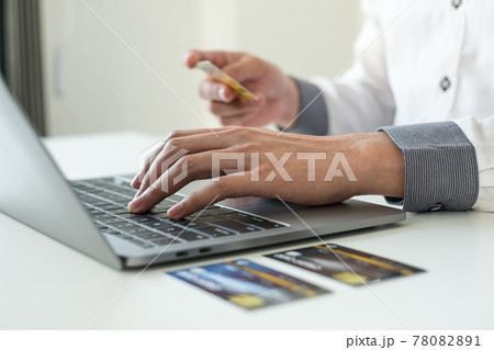 The businessman's hand is holding a credit card and using a laptop for online shopping and internet payment The businessman's hand is holding a credit card and using a laptop for online shopping and internet payment 78082891