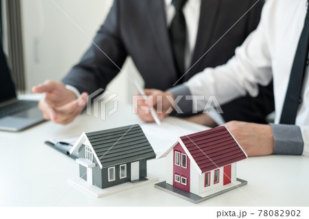 A real estate agent with a House model is talking to clients about buying home insurance. Real estate Home insurance concept A real estate agent with a House model is talking to clients about buying home insurance. Real estate Home insurance concept 78082902