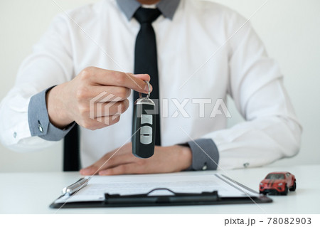 Car dealer businessman holding a car key. Car loan and insurance concept Car dealer businessman holding a car key. Car loan and insurance concept 78082903