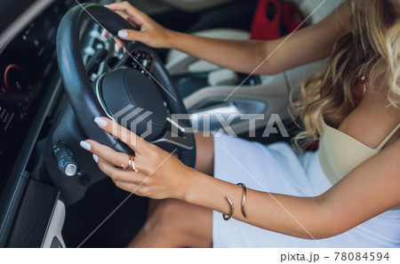 Close-up of a woman's hand on steering wheel in a modern car. Close-up of a woman's hand on steering wheel in a modern car. 78084594