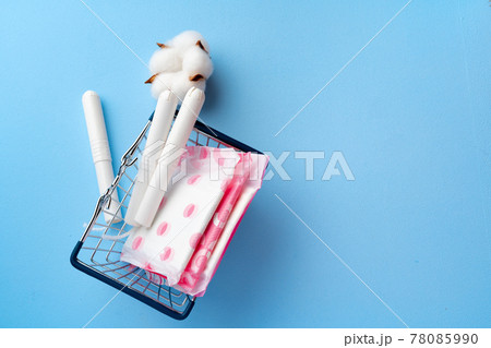 Female pads and tampons on blue paper background 78085990