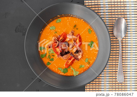 Tom yam Thai soup in black bowl served on gray background 78086047
