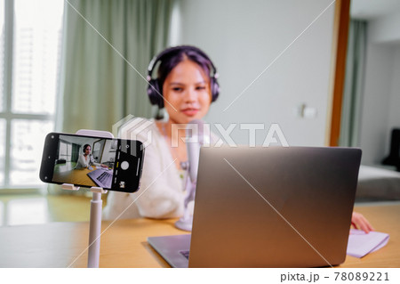 Asian blogger, podcaster or vlogger looking at camera and talking on video shooting with technology Asian blogger, podcaster or vlogger looking at camera and talking on video shooting with technology 78089221